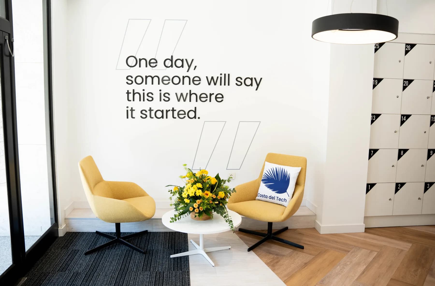 Two yellow lounge chairs beside an FJX wall statement
